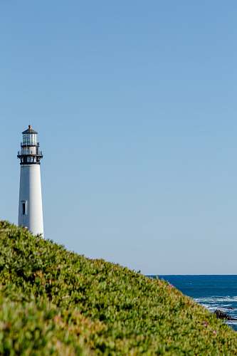 blue lighthouse beside body of water during day time lighthouse