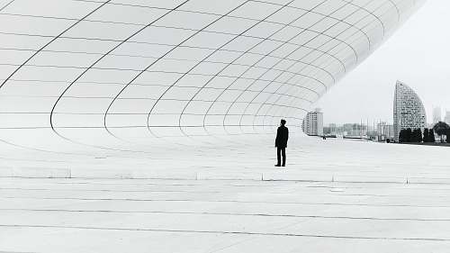 grey person standing in a middle of white plate field architecture