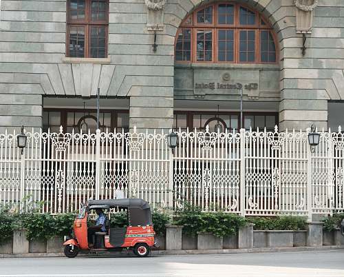 car red auto rickshaw parked in front of concrete structure architecture