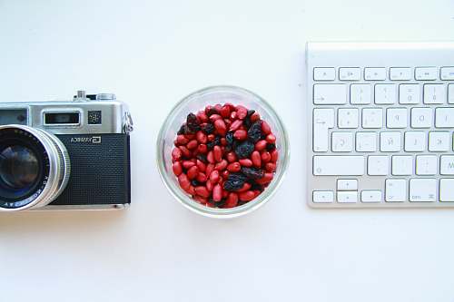 electronics black and gray SLR camera and white keyboard keyboard