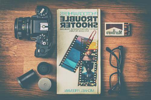 glasses Photographers Trouble Shooter book between DSLR camera, Marlboro match box and eyeglasses matches
