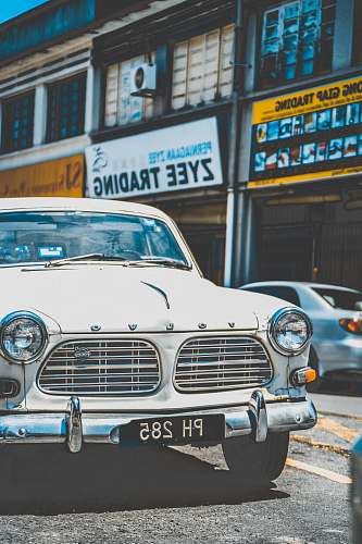 automobile classic white vehicle parked near building during daytime vehicle
