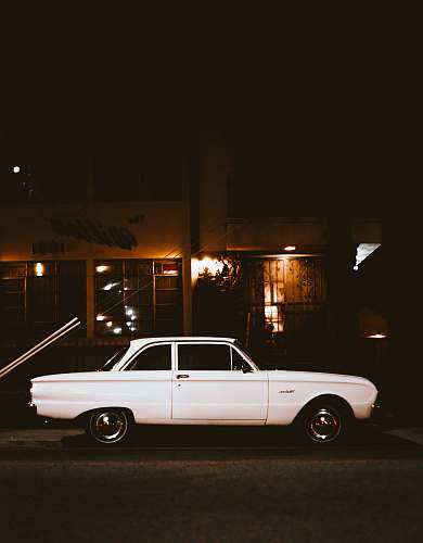 automobile white car parked beside the street sedan