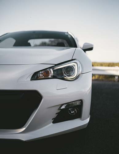 automobile white coupe parked near road barrier transportation