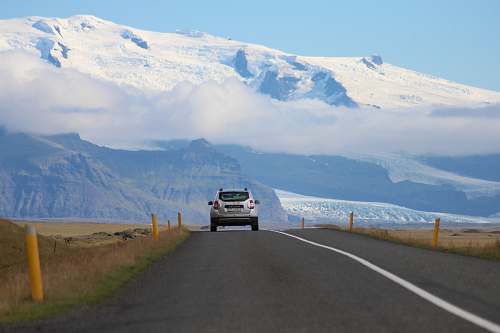 road white SUV passing through roadway mountain