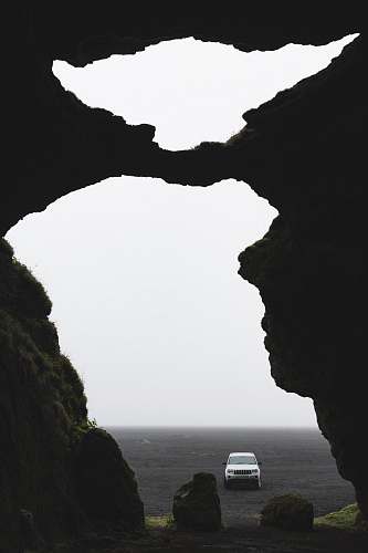 ocean white car between rock formation human