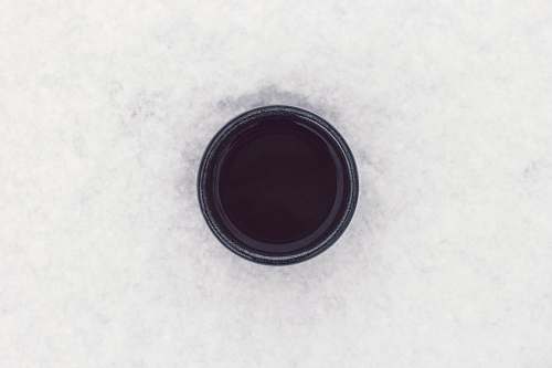 cold round black container on top of white surface drink