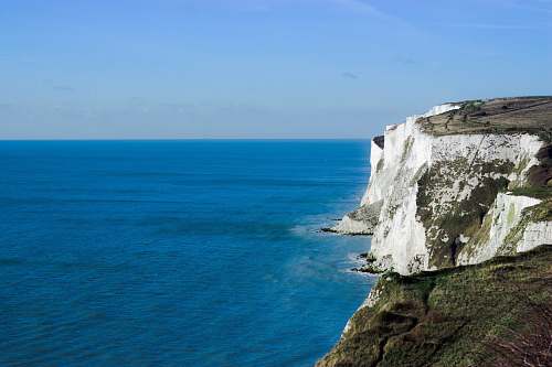 blue bird's eye photography of mountain near body of water coast