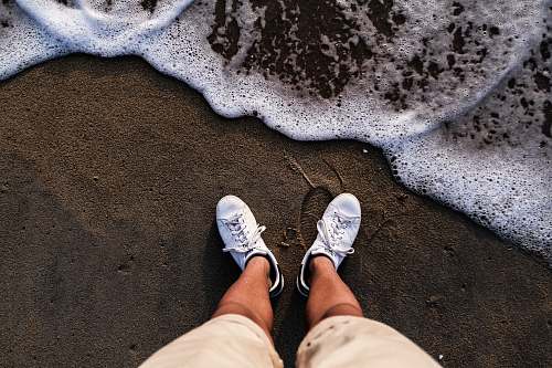 footwear person wearing white shoes standing on sea shore shoe