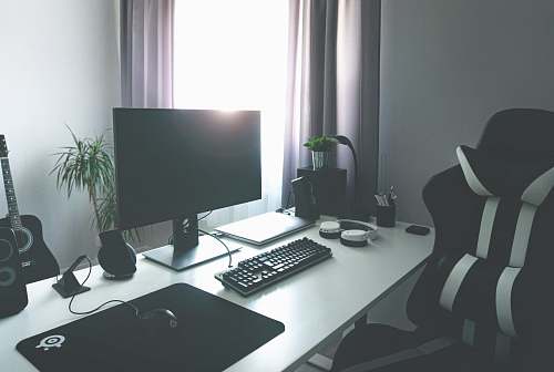 keyboard flat screen monitor turned-off near corded keyboard and mouse on white table beside black and white rolling chair hardware