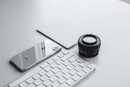keyboard silver iPhone X beside camera lens and Apple Keyboard shade