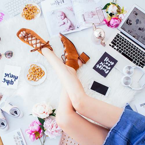 tea woman wearing brown open-toe chunky sandals sitting beside white smartphone, headphones and laptop legs