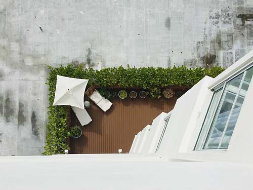 building high-angle photography of chaise lounge and umbrella at daytime balcony