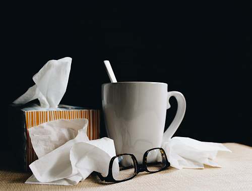 goggles white ceramic mug on white table beside black eyeglasses coffee cup