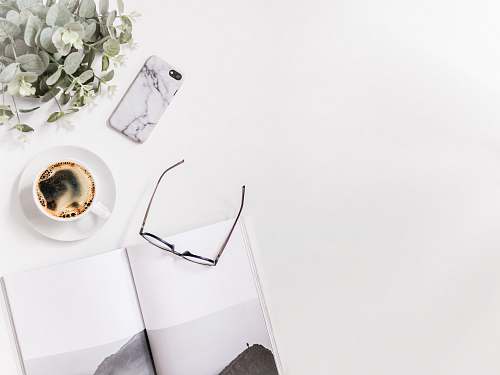 phone clear eyeglasses next to white coffee cup cell phone