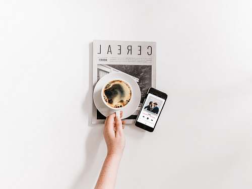 white person holding a cup of coffee reading