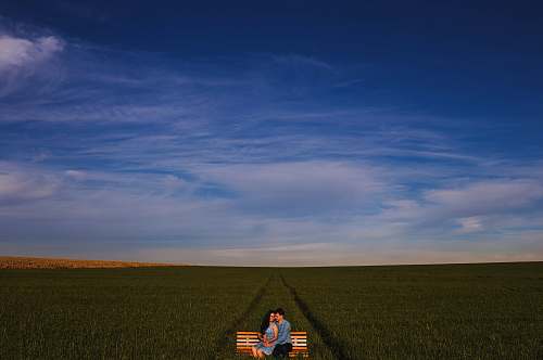 brazil photo of two man and woman sitting on bench on grass field love
