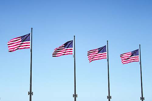 emblem four USA flags under blue sky pole
