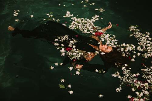 woman woman wearing black suit floats on the water flower
