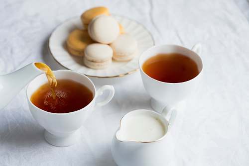 tea two cups of coffee beside the macaroons on plate milk