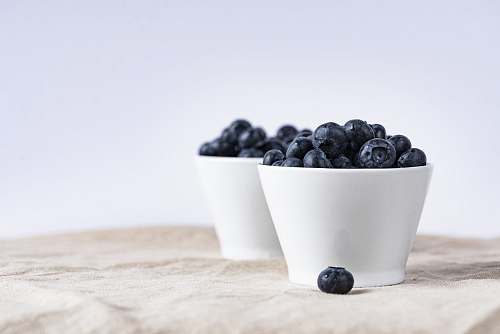 fruit two white ceramic cup filled with blueberries fruit place on brown textile blueberry