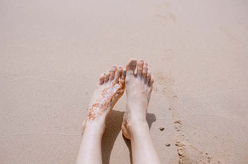 feet selective focus photography of feet with tattoo on sea sand sand