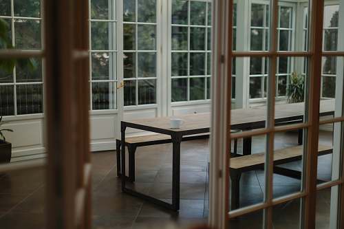 table brown wooden table beside glass paneled wall dining table