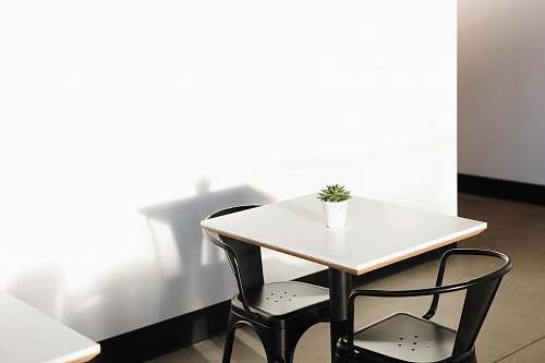 table square white wooden table with two black metal chairs dining table