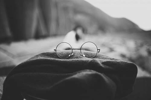 black-and-white grayscale photo of hippie eyeglasses on cloth grey