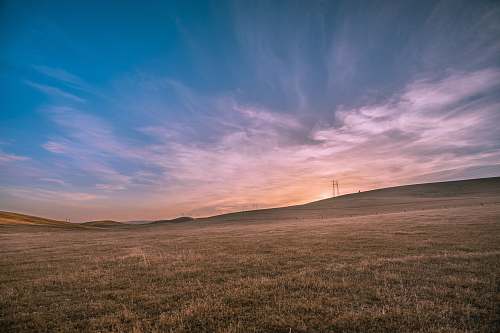 field landscape photography of brown field under blue sky outdoors
