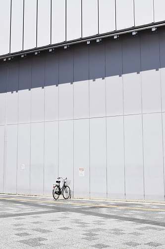 building black commuter bike parking beside wall at daytime japan