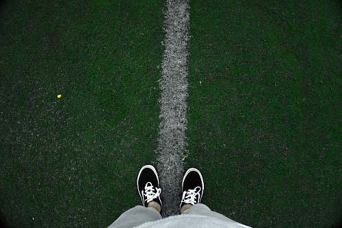shoe person wearing black low-top sneakers standing on green grass at daytime clothing