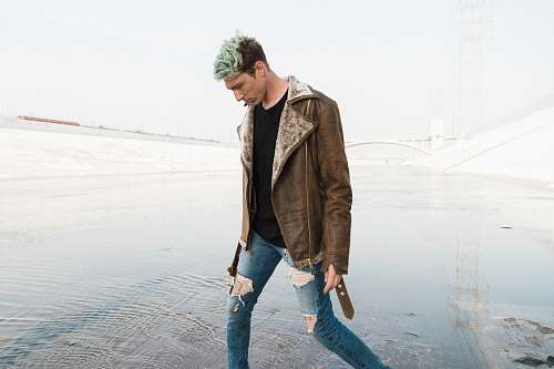 person man in brown jacket walking near shore people