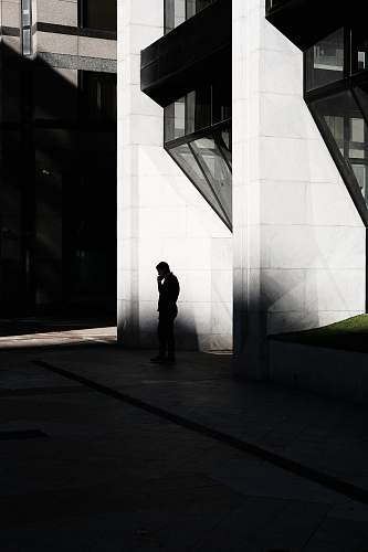 person man standing near buildings in grayscale photography silhouette