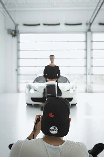 people man taking a picture of standing man in front of car inside room person