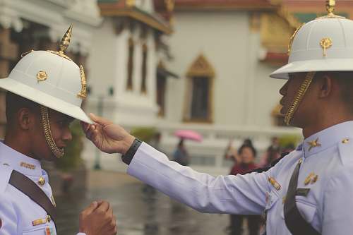 person officer in white uniform touching man's white hat people