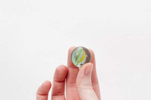 person person holding yellow and green marble toy finger
