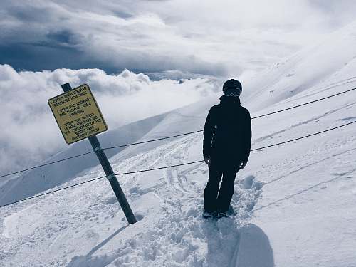 nature person in snowsuit standing beside sign outdoors