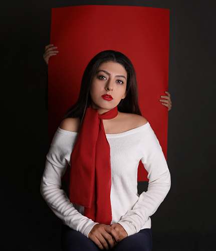 person woman in white long-sleeved top and red scarf in front of red paper board people