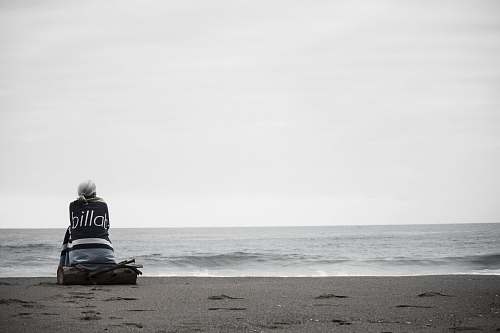 person woman sitting near seashore during daytime beach