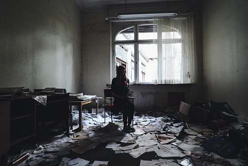 person woman sitting on chair surrounded by papers on floor flooring