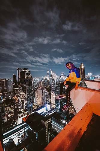 building woman sitting on cliff building city