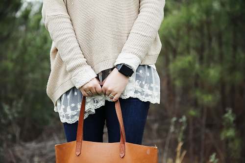 person woman standing holding a brown leather tote bag people
