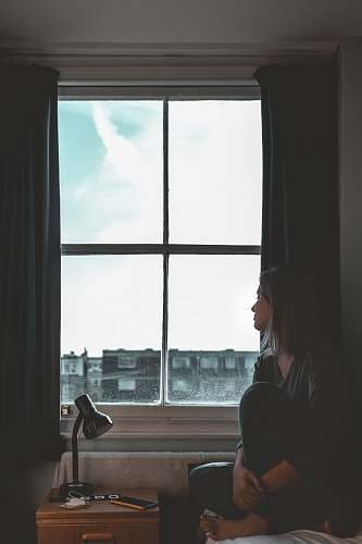 person woman wearing black leggings sitting besides window white