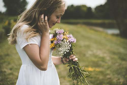 person woman wearing white shirt holding flower wile smelling people