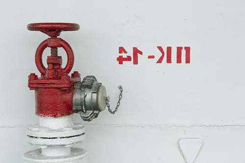 plumbing red and white fire hydrant beside white wall wall