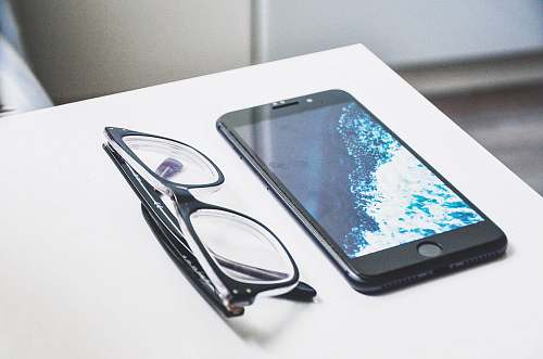 computer black eyeglasses near iPhone electronics