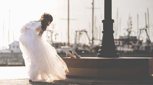 bride woman taking off her shoe near post white
