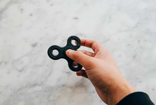 toy person using black fidget spinner holding