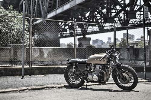 vehicle brown standard motorcycle near wire fence during daytime transportation